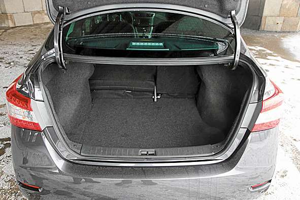 Nissan Sentra. Багажник очень вместительный, но часть полезного объема «съедают» арки и развитые петли. Спинки при складывании образуют ступень. 
