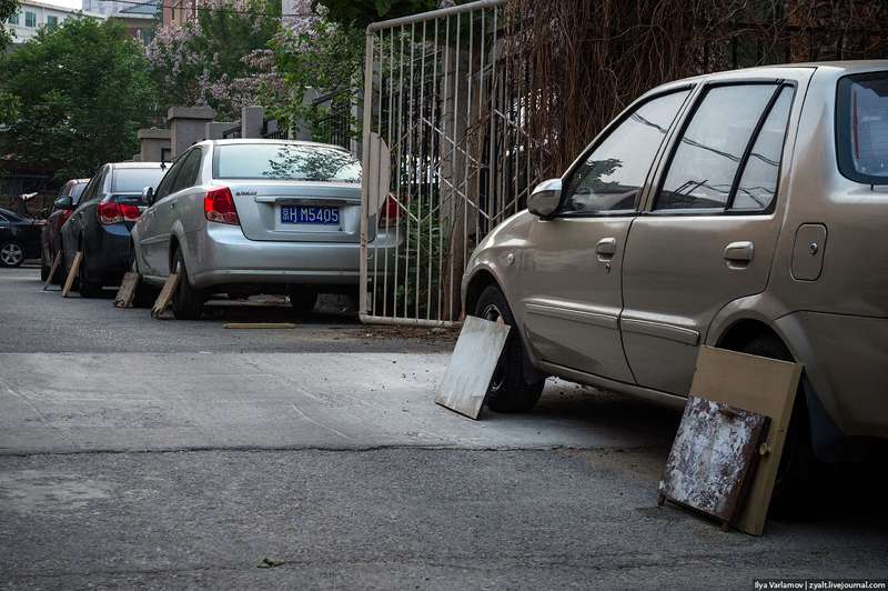 Китайцы прикрывают колеса своих автомобилей на парковке дощечками, чтобы их не «пометили» дворовые собаки. Фото: Varlamov.ru